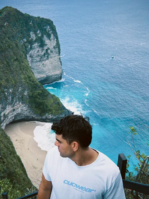 Chico con la camiseta Skyblue Ocean mirando el mar desde unas escaleras sobre un acantilado