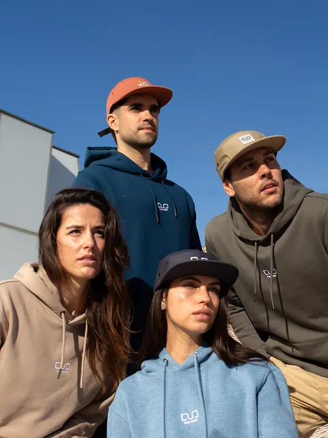 Cuatro personas con hoodies de colores contra un cielo azul intenso