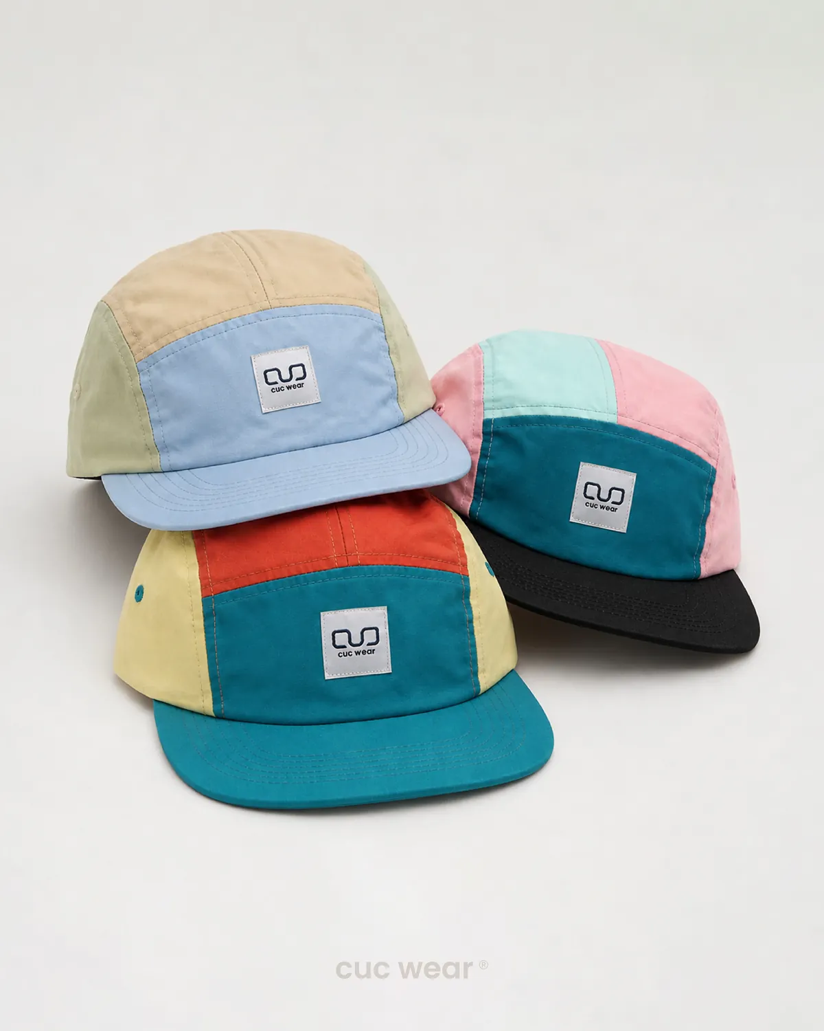 Tres gorras de cinco paneles de colores sobre un fondo claro